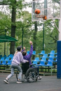 Boy in wheelchair playing basketball with friend