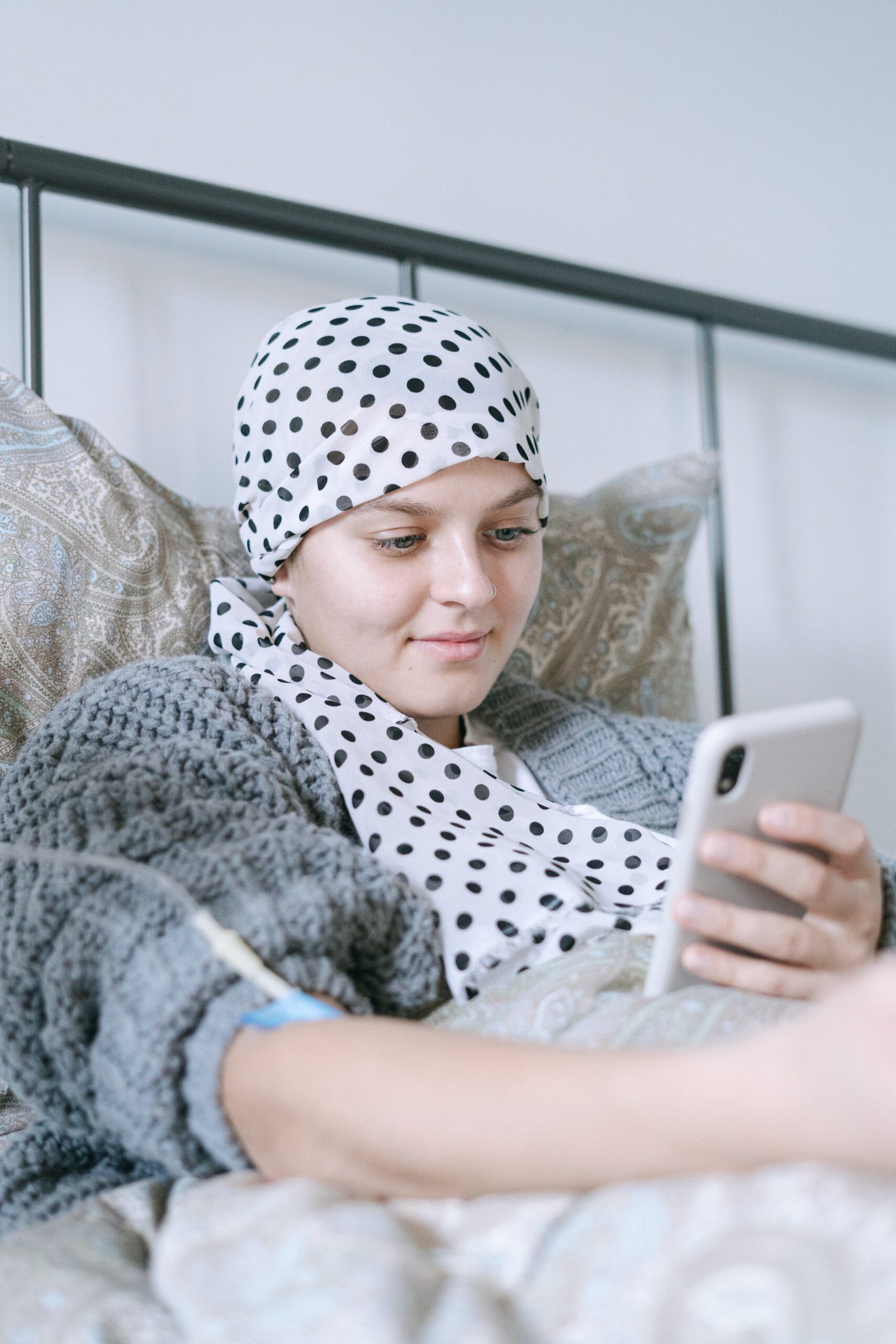 Young woman with cancer in bed on phone